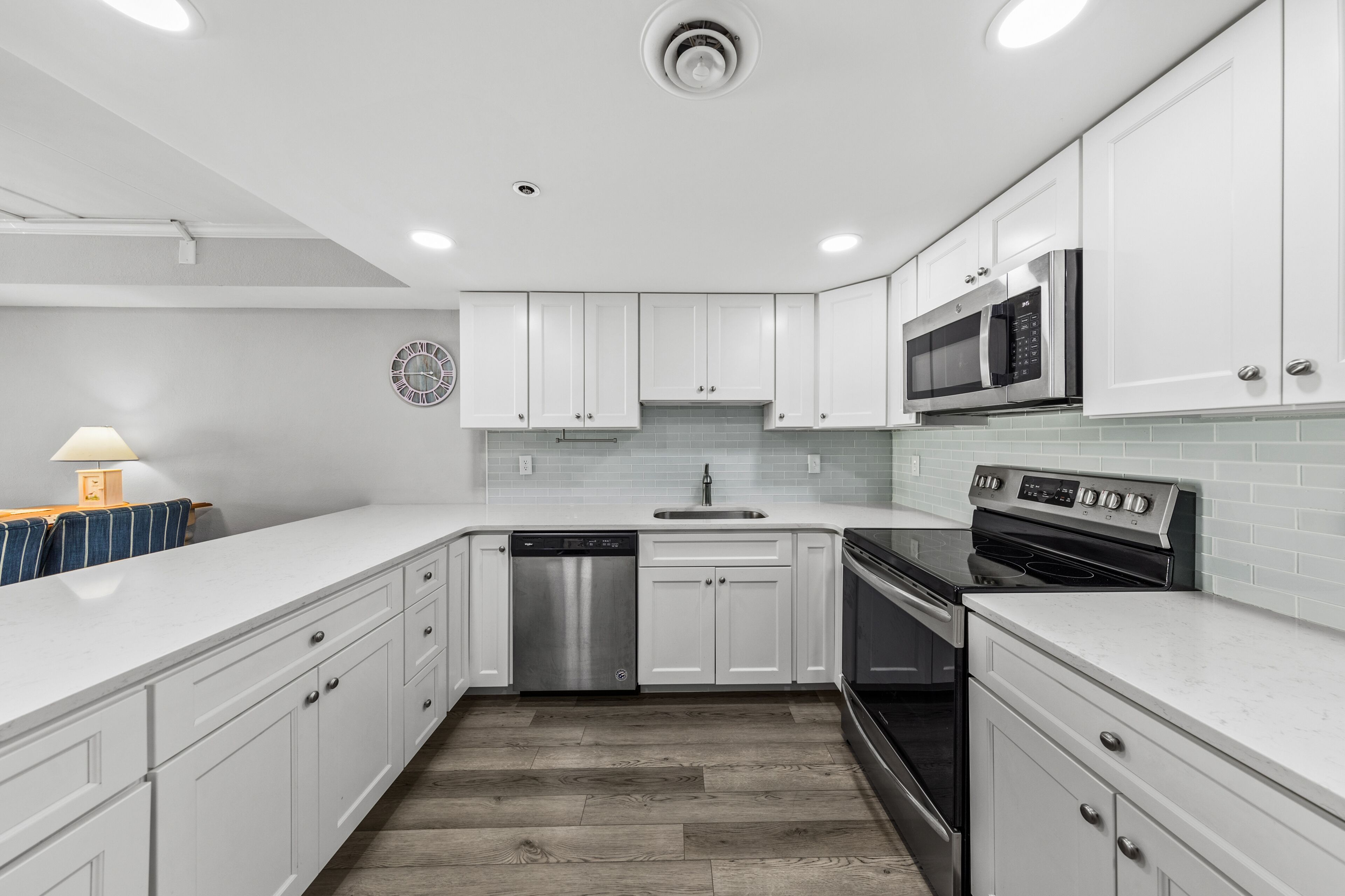 A modern kitchen with white cabinetry, stainless steel appliances, and a tiled backsplash.