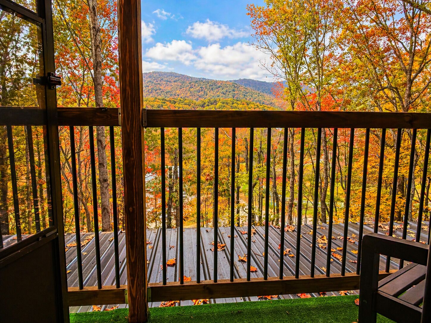 Una terraza de madera con vistas a un área boscosa y montañas.