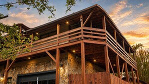 Un bâtiment à deux étages avec une façade en pierre, une terrasse en bois et un garage.