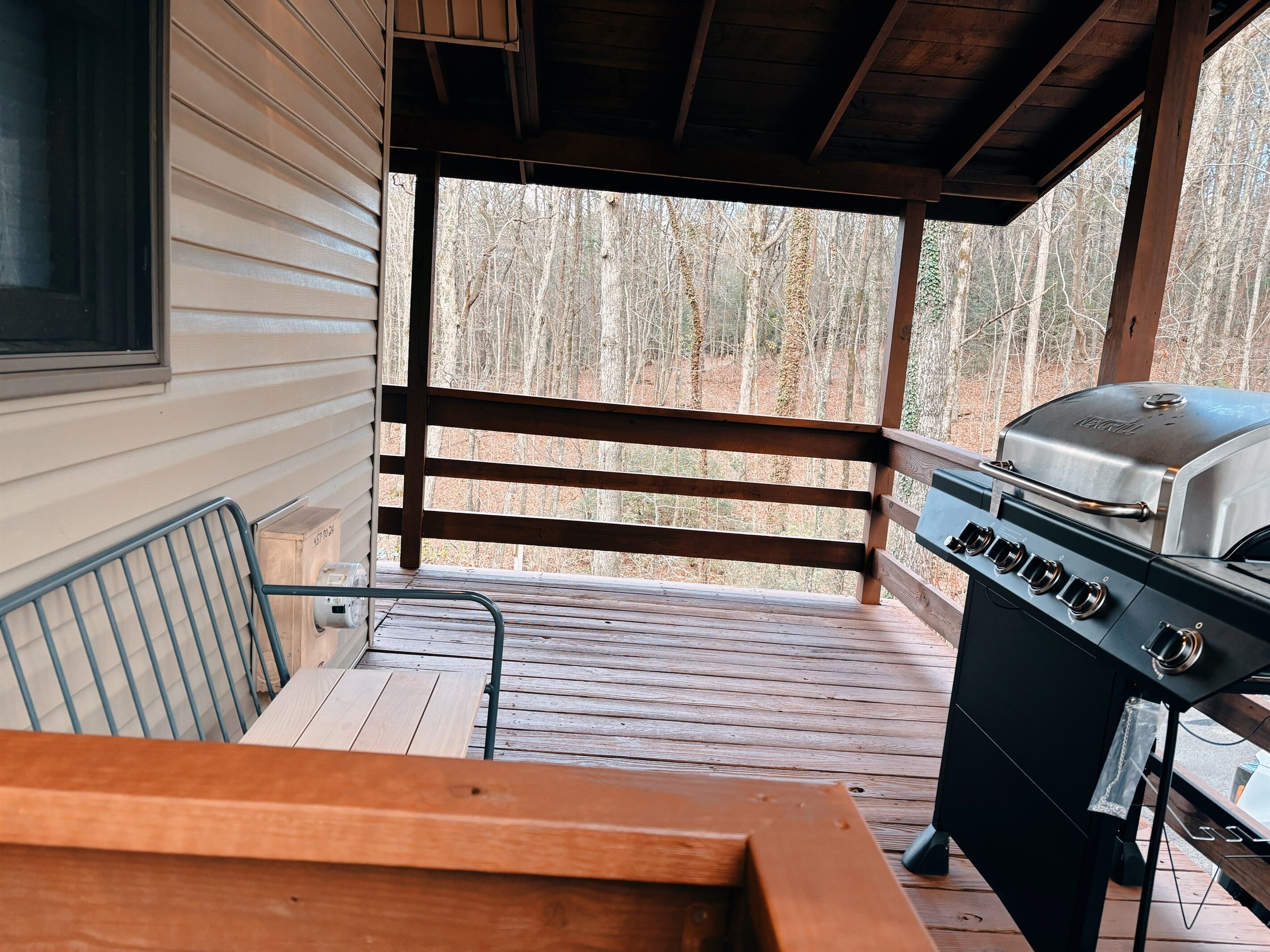 Un espacio al aire libre techado con una parrilla y un piso de madera.