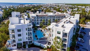 A modern hotel with multiple floors, a central swimming pool, and a landscaped courtyard. - The Pointe by Southern Vacation Rentals (Panama City Beach)