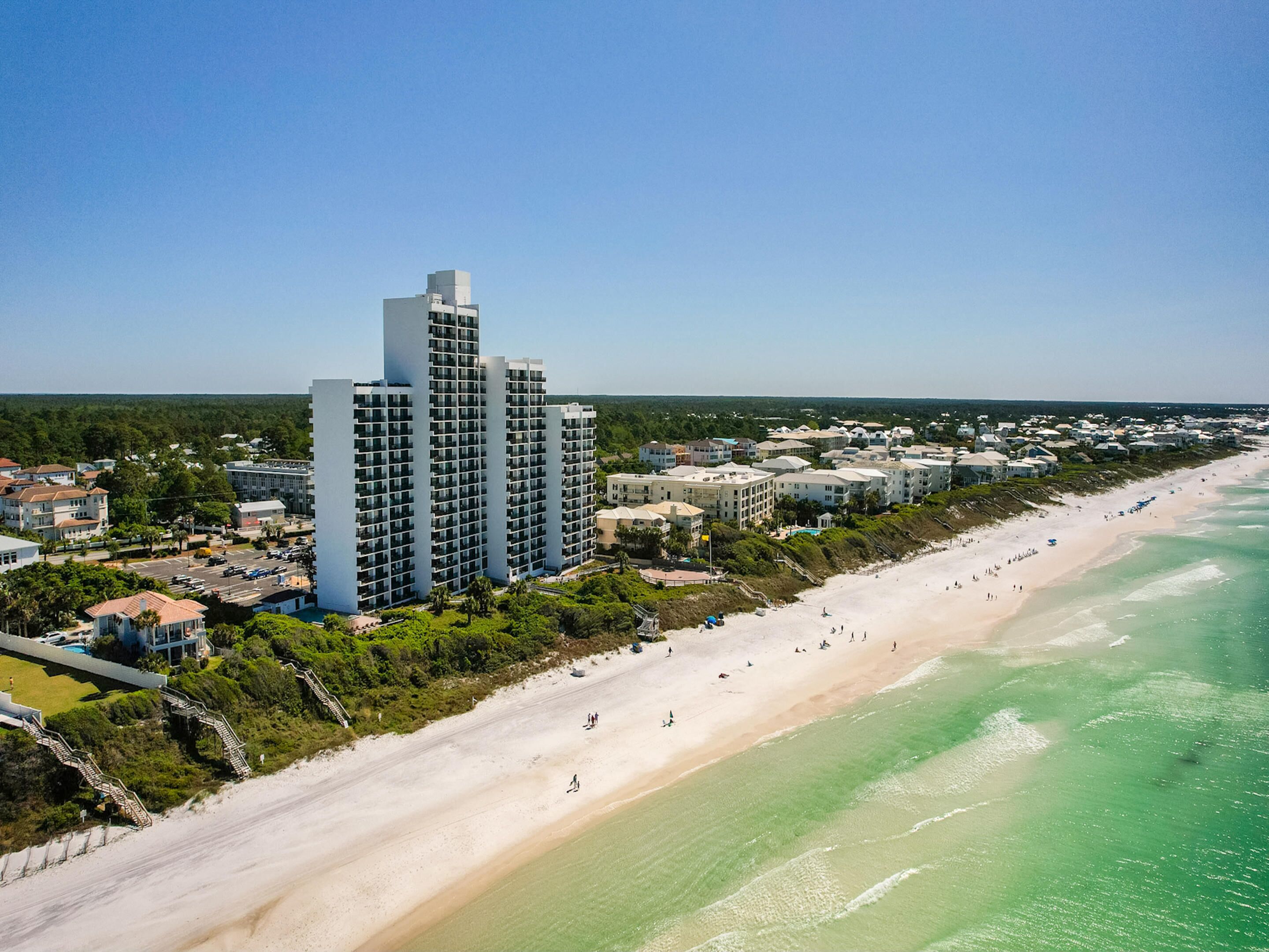 A coastal area with a beach, a row of high-rise buildings, and a dense residential area.
