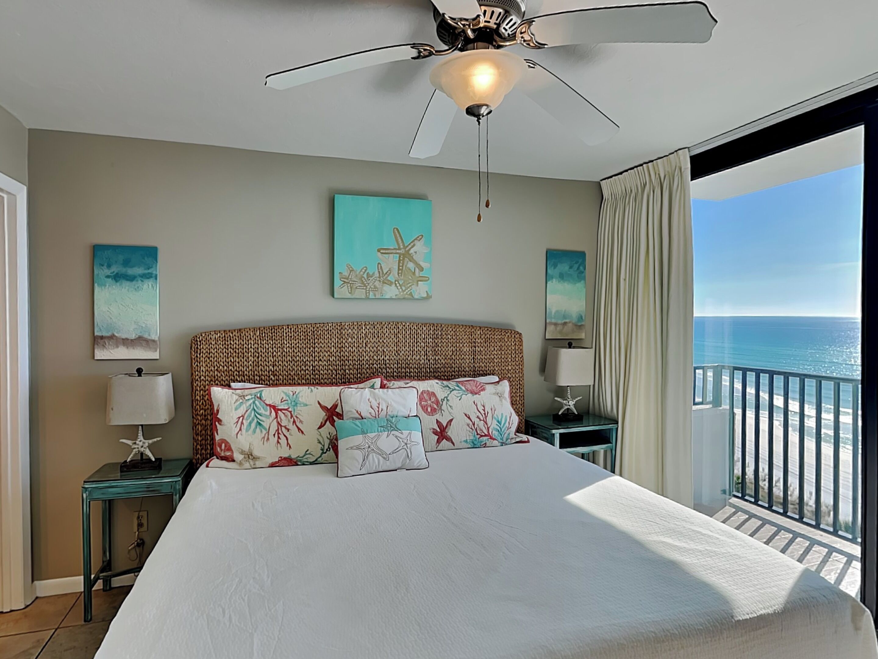 A bedroom with a bed, a ceiling fan, and a view of the ocean.