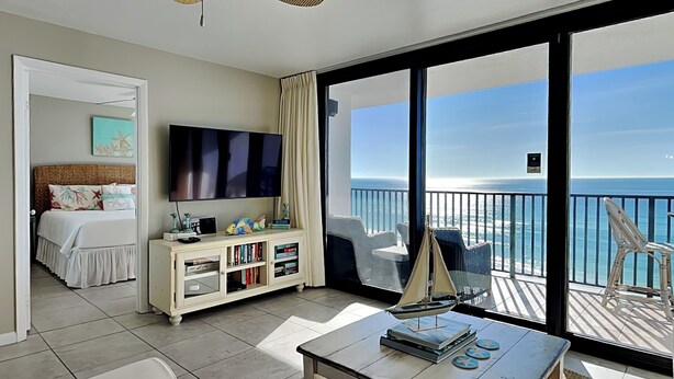 Une chambre d’hôtel avec un balcon, un lit, une télévision, une bibliothèque et une vue sur l’océan.