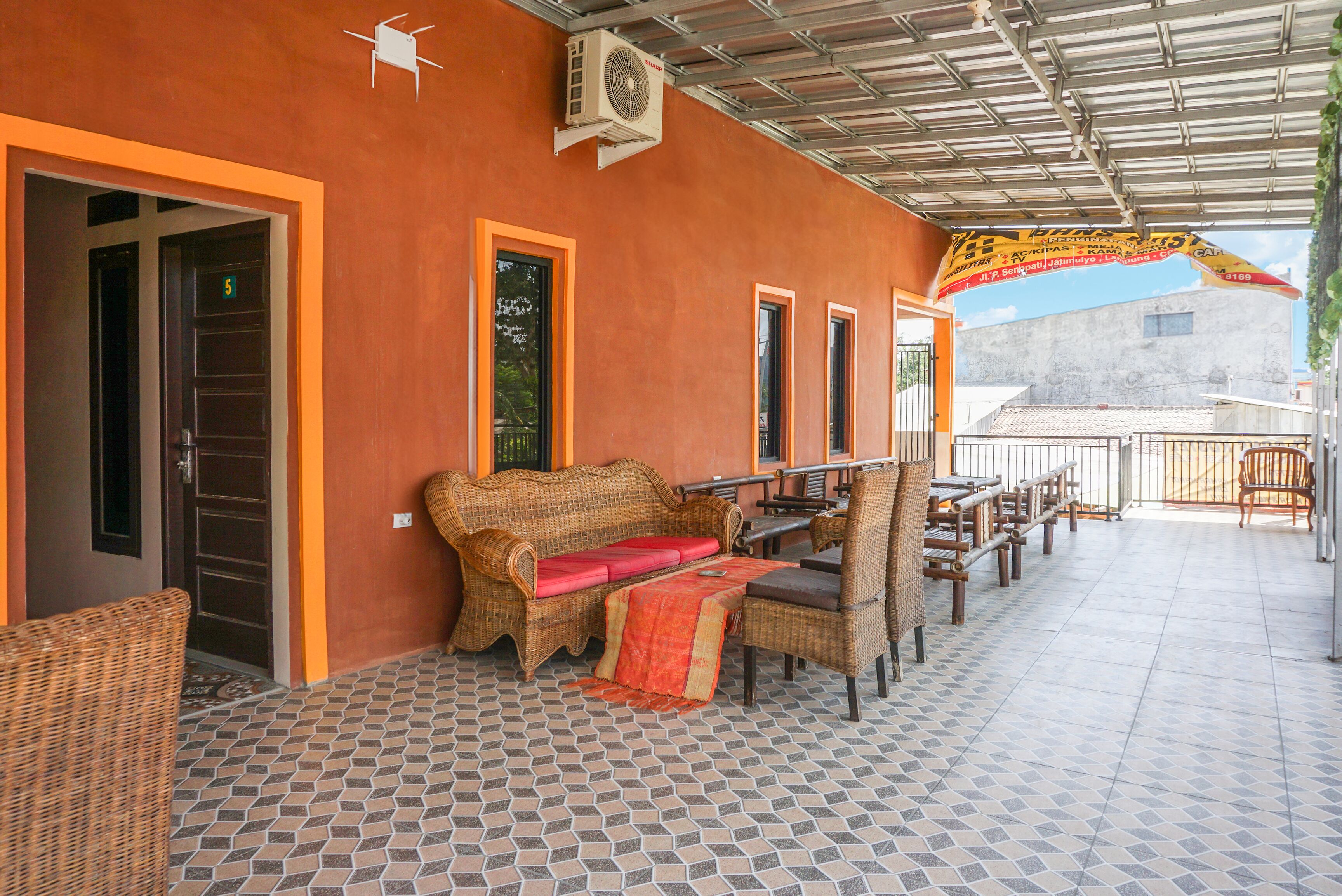 A covered outdoor seating area with wicker furniture, a tiled floor, and a metal roof.