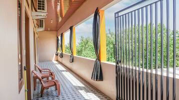 A balcony with a tiled floor, a metal gate, and a view of greenery.