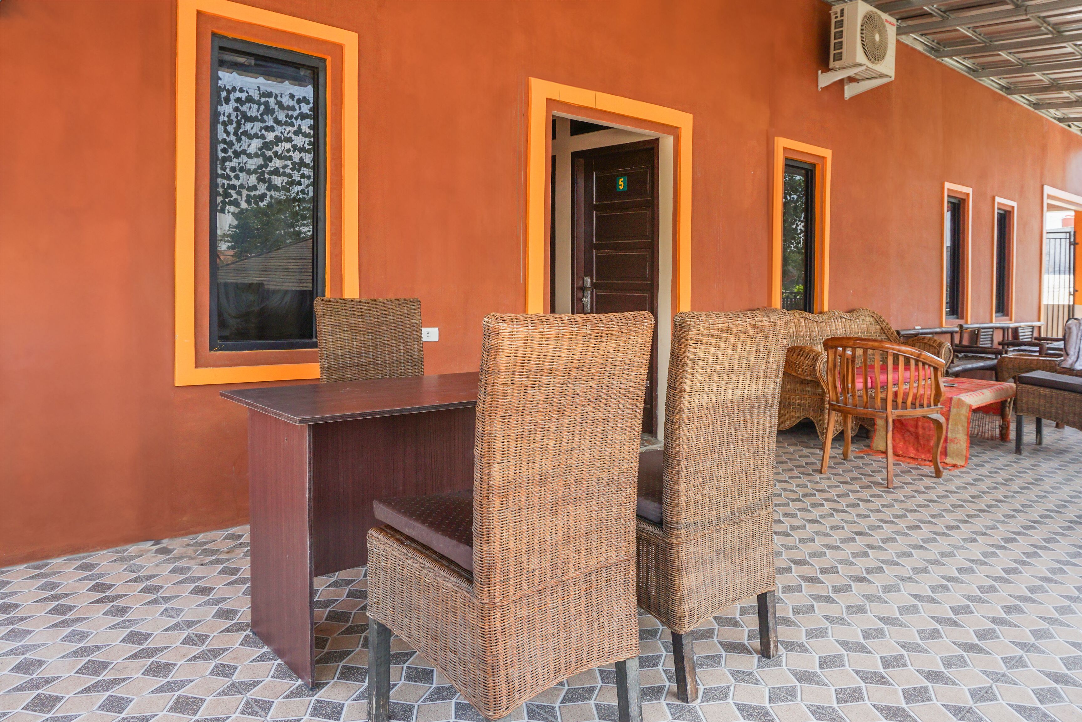 A covered outdoor seating area with wicker furniture and a tiled floor.