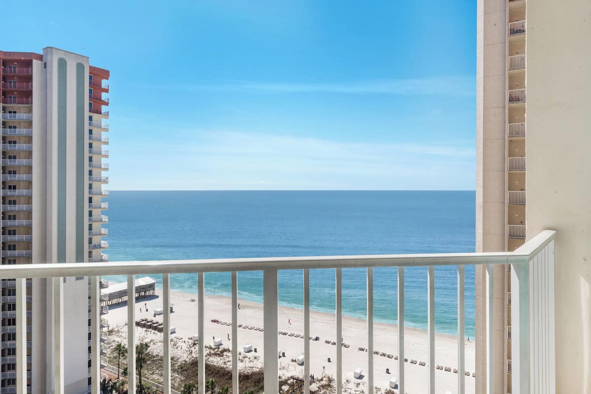 A high-rise hotel with balconies overlooking a beach.