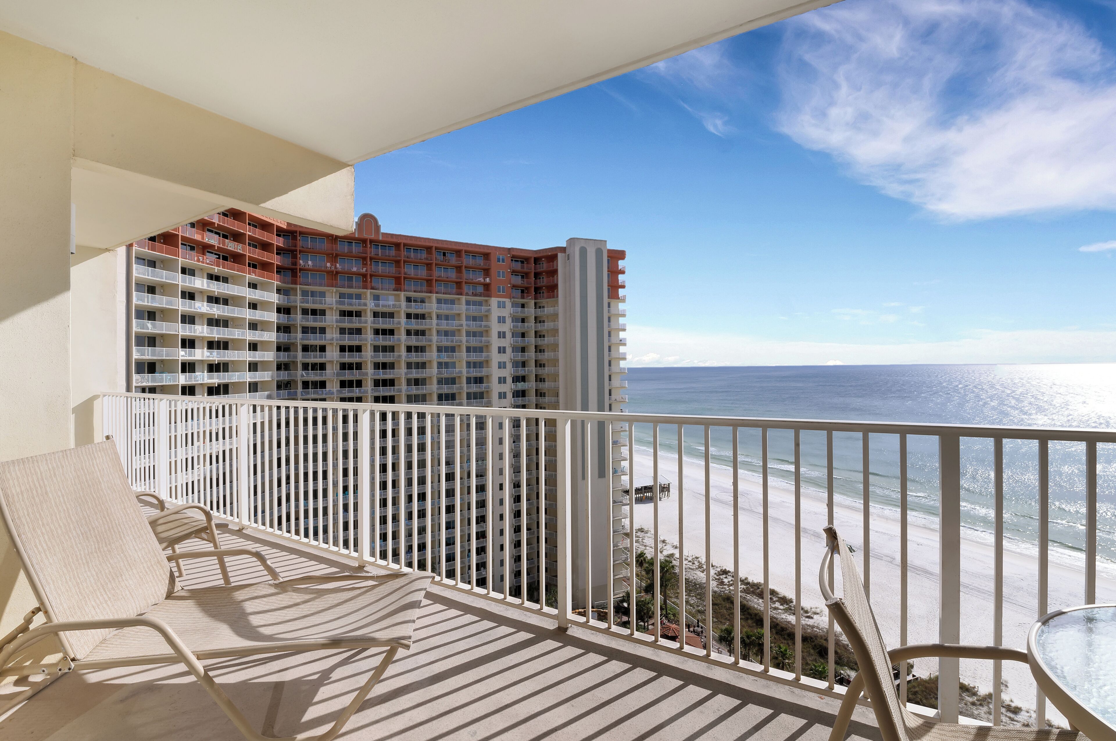 A balcony with a view of the ocean and a high-rise building.