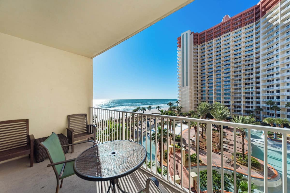 A balcony with a view of the ocean and a high-rise building.