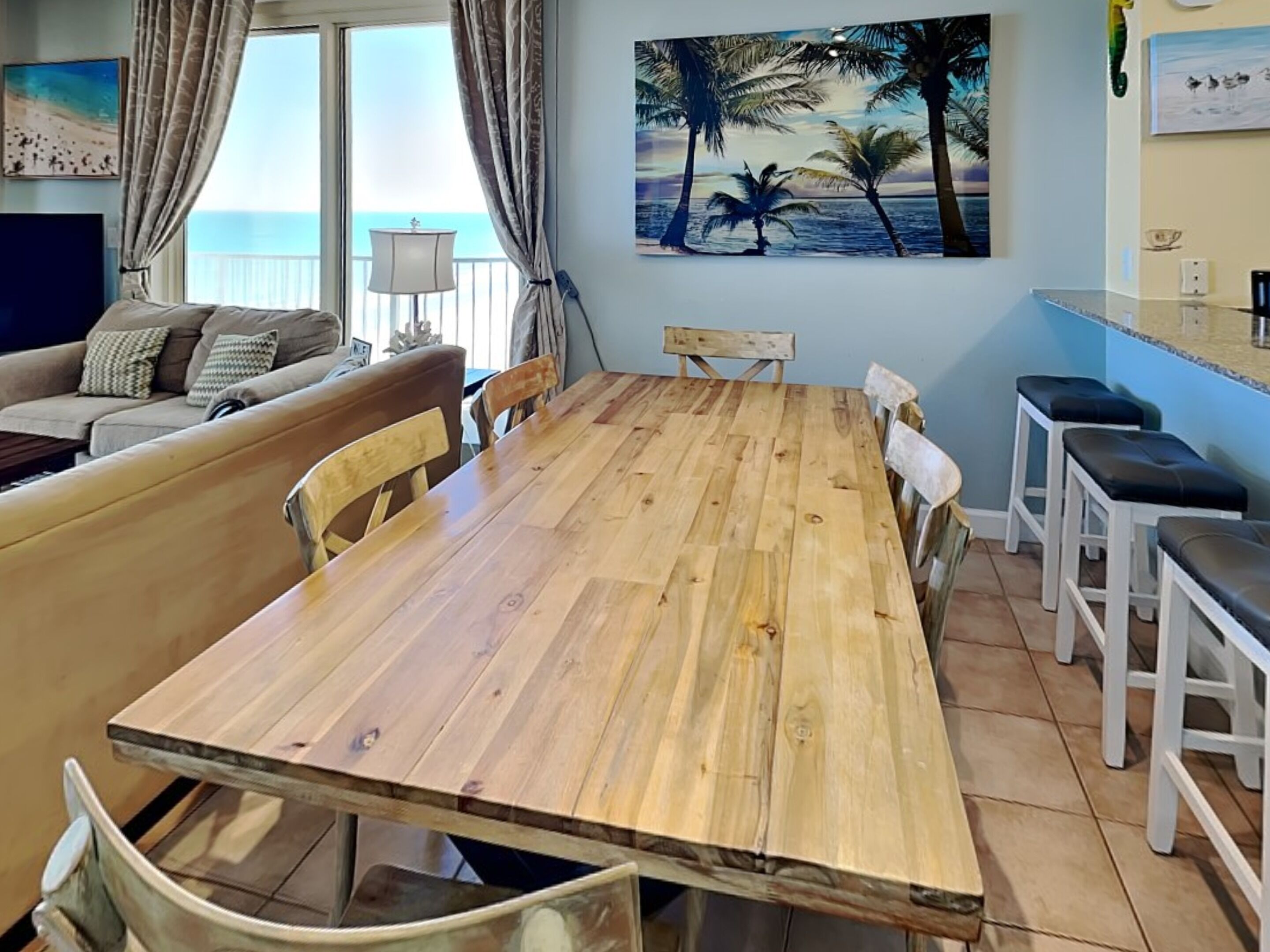 A dining area with a wooden table, chairs, and a view of the ocean through large windows.