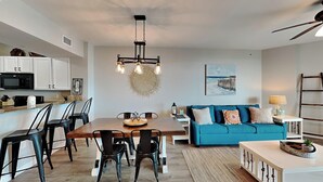 A modern kitchen with white cabinets, a dining table with chairs, a blue sofa, and a ceiling fan. - The Palms of Destin by Southern Vacation Rentals (Destin)