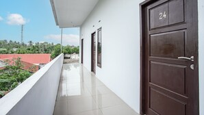 A corridor with a tiled floor, a balcony with a white railing, and two doors with the number 24 on them. - Hotel O Owo Guest House Syariah (Jambi)