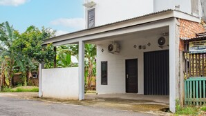 A white building with a covered entrance, two black doors, and a signboard. - Hotel O Owo Guest House Syariah (Jambi)