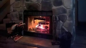 A stone fireplace with a fire, a wooden shelf above it, and a staircase to the left. - Private Cottage minutes from Moraine State Park and McConnell's Mill State Park. (Portersville)