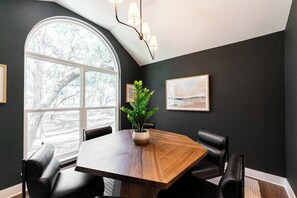 A conference room with a large wooden table, black leather chairs, a potted plant, and framed artwork on the walls. - Secluded Hill Country Luxe: Vibes, Pool, Best Spot (Austin)