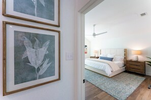 A bedroom with a bed, bedside tables, a ceiling fan, and framed artwork on the wall. - Secluded Hill Country Luxe: Vibes, Pool, Best Spot (Austin)