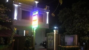 A building with a brightly lit sign, a gated entrance, and a small garden area.