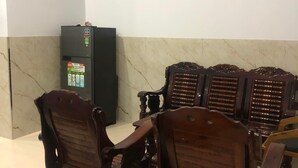 A room with a marble wall, a black refrigerator, and wooden chairs with cushioned seats.