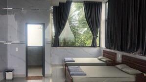A hotel room with a large window, two beds, a ceiling fan, and a marble wall.