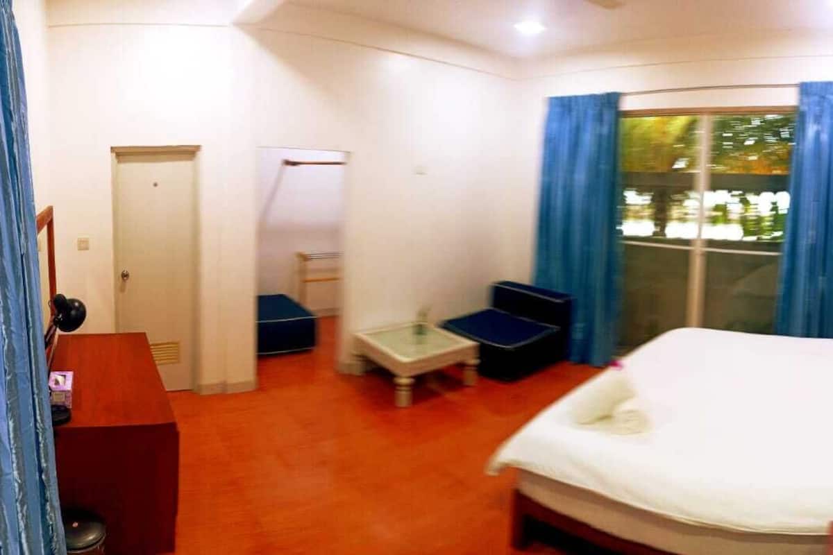 Een compacte hotelkamer met een bed, een bureau, een stoel en een tafeltje.