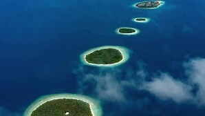 Une chaîne de petites îles circulaires aux eaux d’un bleu limpide et à la végétation luxuriante.