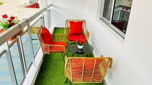 Ein Balkon mit Korbstühlen, einem kleinen Tisch und einem Blumentopf.