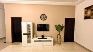 Ein modernes Wohnzimmer mit Flachbildfernseher, einer dekorativen Uhr und einem Blumentopf.