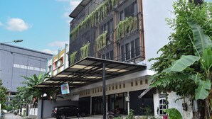 A modern building with a covered entrance, large windows, and greenery on the facade. - OYO 93503 Lotte Residence (Palembang)