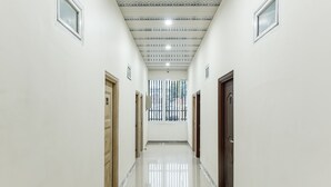 A corridor with white walls, wooden doors, and a tiled floor. - OYO 93503 Lotte Residence (Palembang)