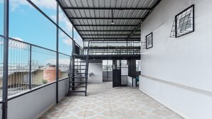 A spacious balcony with patterned floor tiles, a metal staircase, and a view of the cityscape. - OYO 93503 Lotte Residence (Palembang)