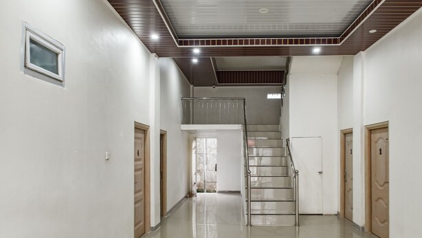 A hallway with a staircase, white walls, and a tiled floor. - OYO 93503 Lotte Residence (Palembang)