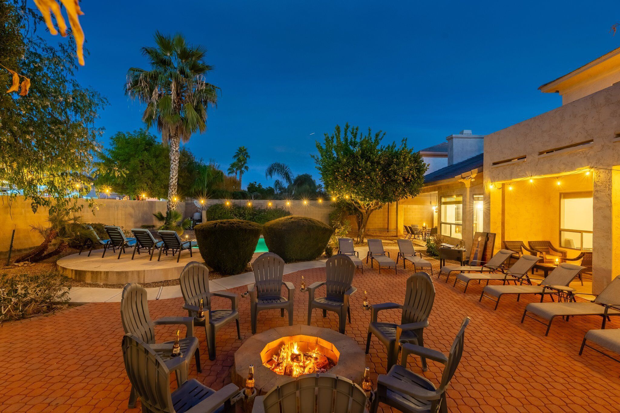 An outdoor patio with a fire pit, lounge chairs, and ambient lighting.