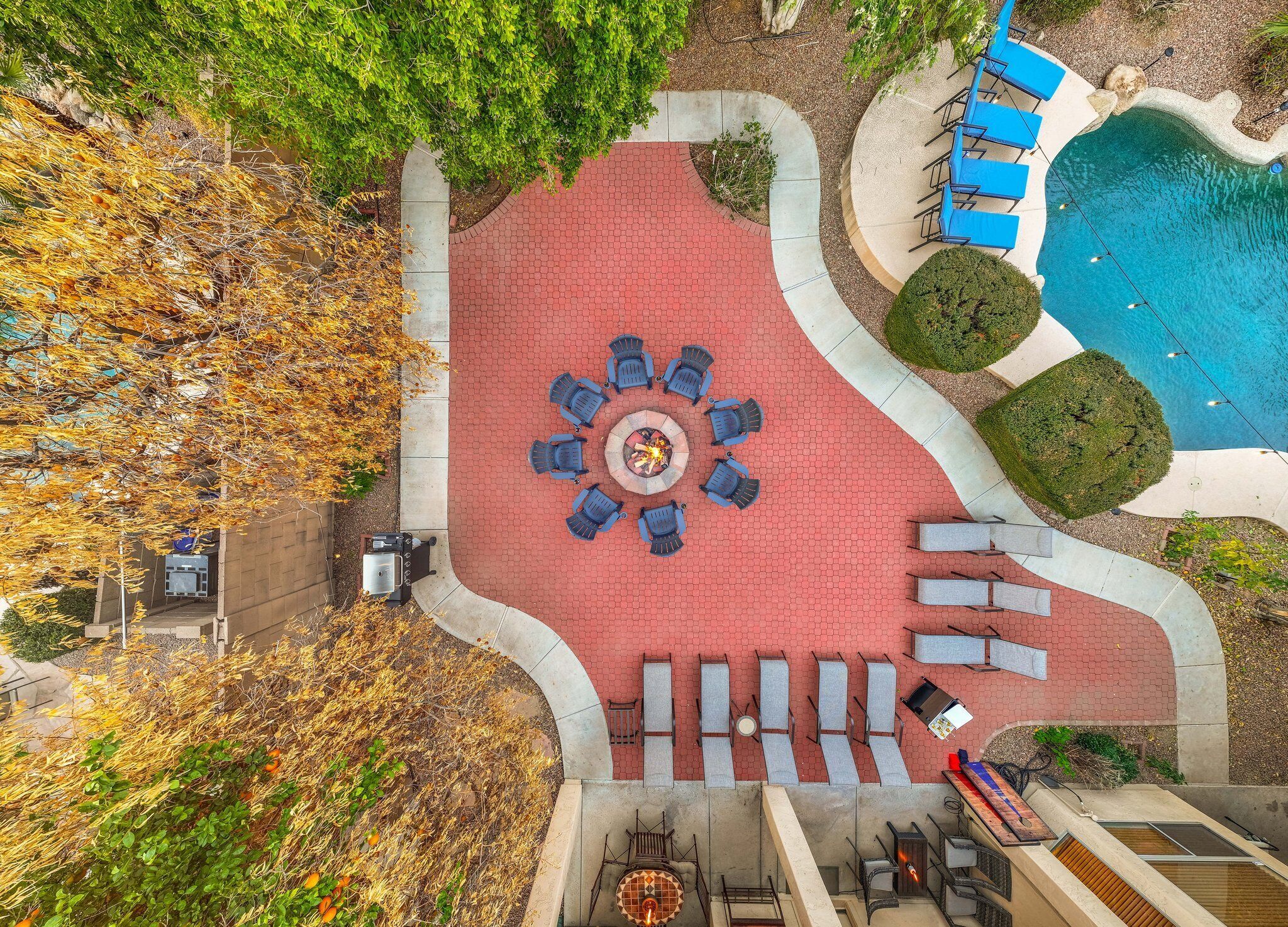 Ein Patio mit Sitzgelegenheiten im Kreis, einem Feuerkorb und einem Pool.