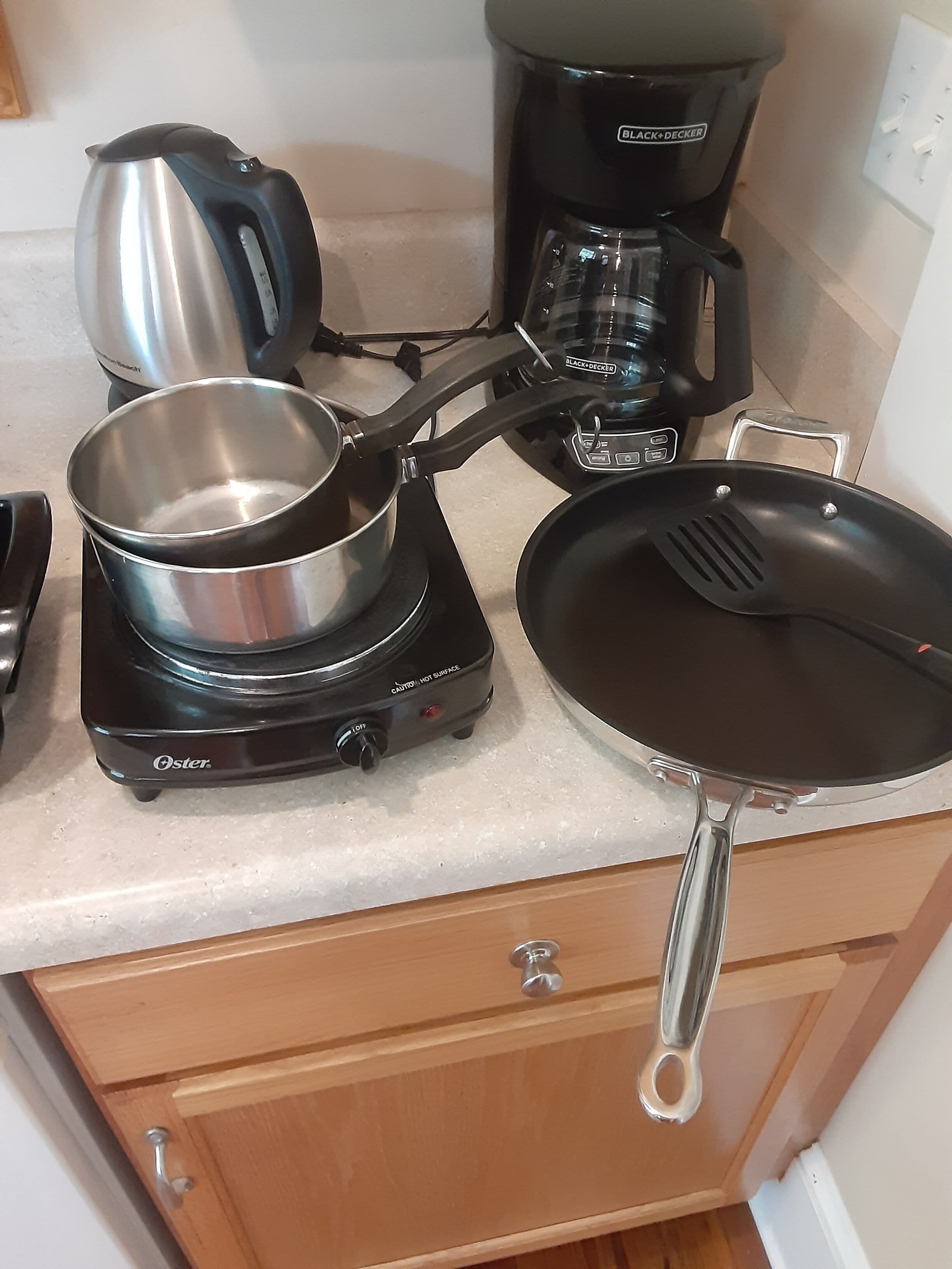A kitchen with a gas stove, a frying pan, a pot, and a coffee maker.