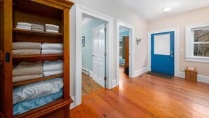 A hallway with wooden flooring, a blue door, and a wooden closet with folded towels. - Private Suite Walk Downtown- Private Bath-Private entrance. (Asheville)