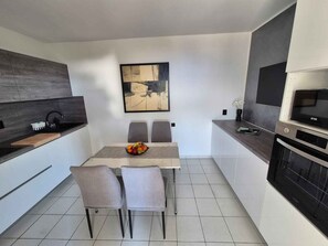 A modern kitchen with a dining table, chairs, and a fruit bowl. - Holiday flat with sea view (Njivice)