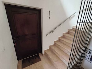 A staircase with a metal handrail and a dark wooden door with a doormat. - Holiday flat with sea view (Njivice)