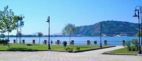 Un camino pavimentado con vistas a un lago y colinas al fondo.
