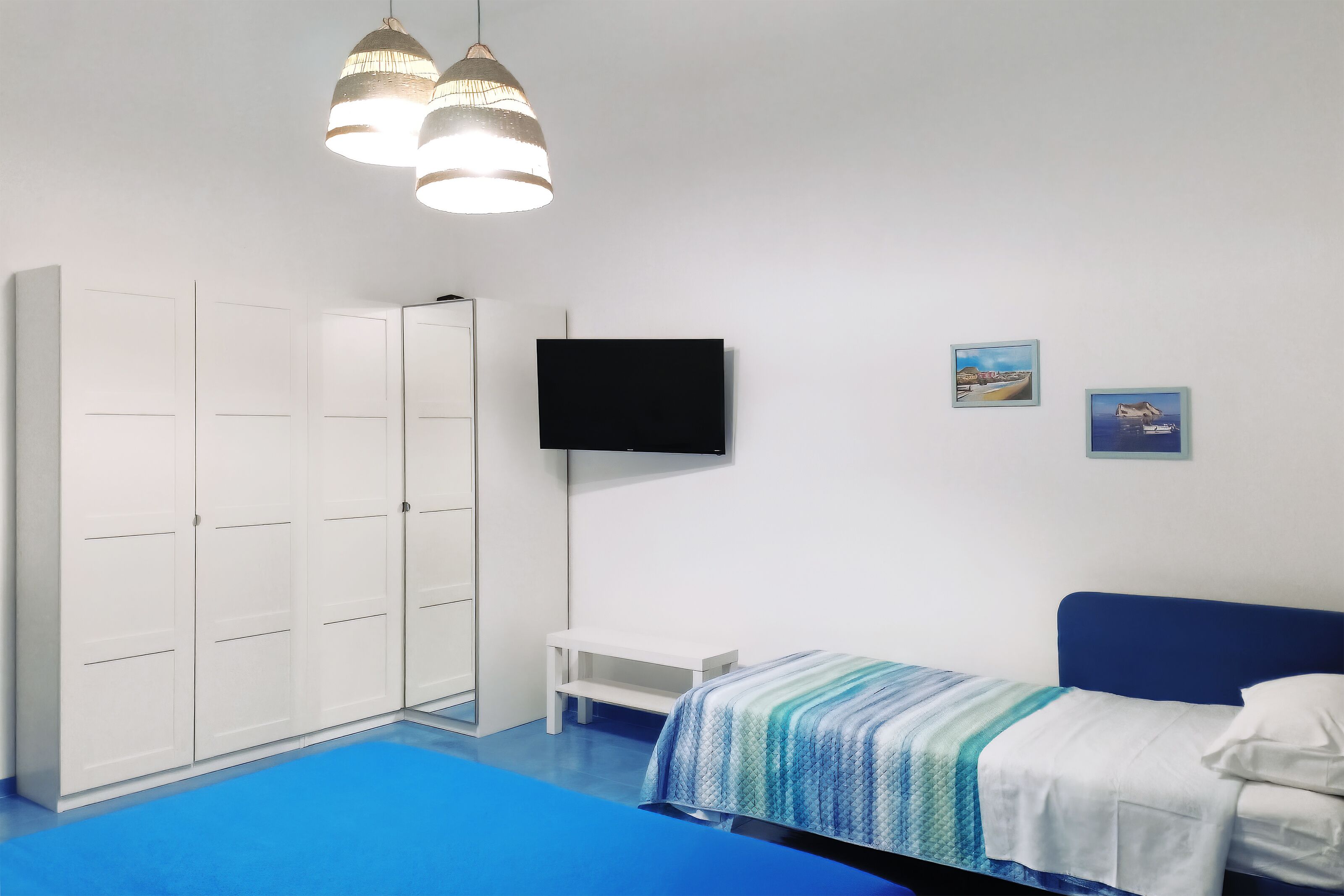 A bedroom with a bed, a TV, a wardrobe, and a bench.
