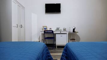 A hotel room with two beds, a desk, a chair, a television, and a mini-fridge.