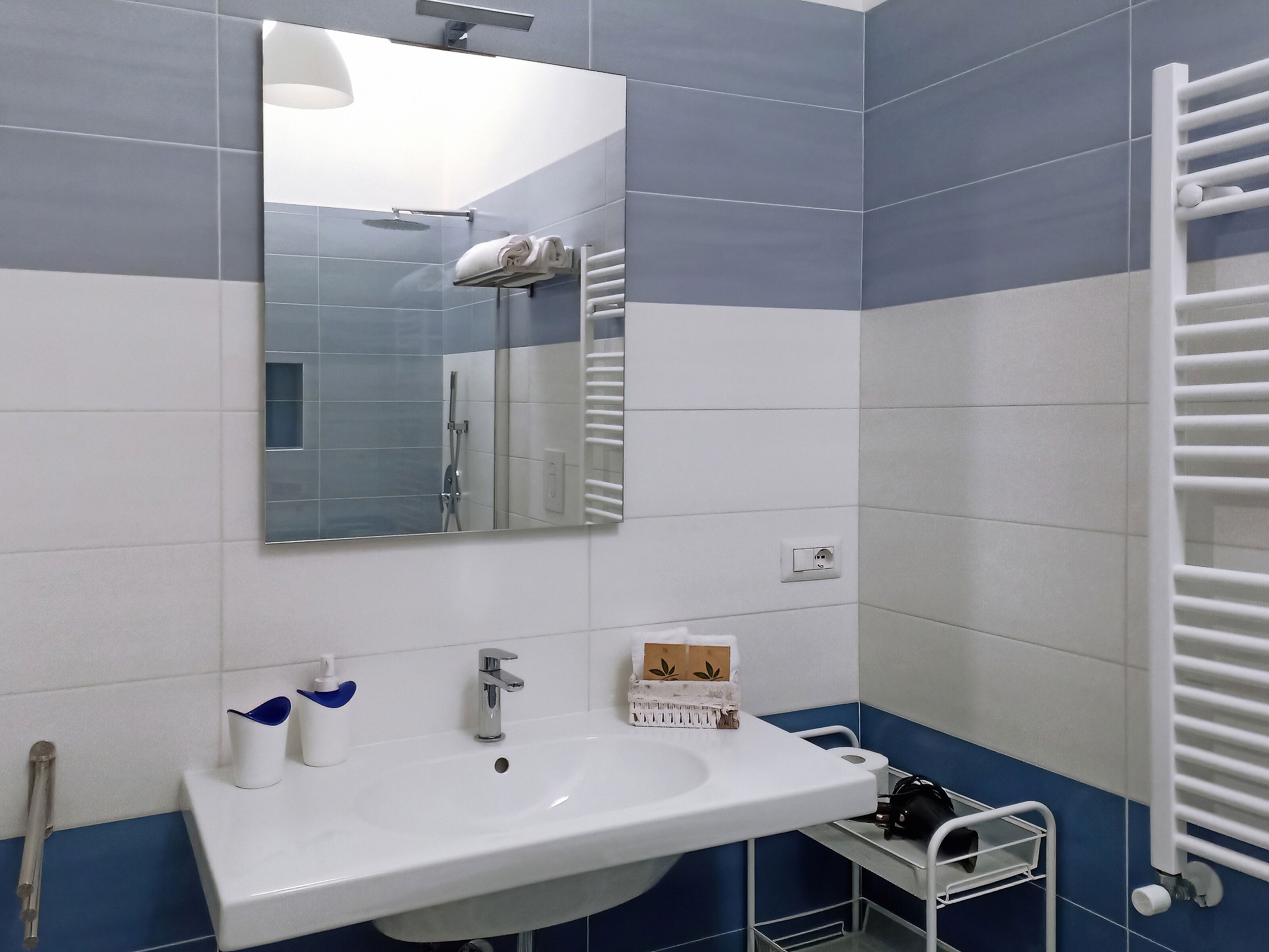 Casa de banho com lavatório branco, espelho e porta-toalhas.