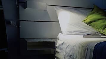 Una cama con cabecera blanca, almohada verde y una lámpara de noche.