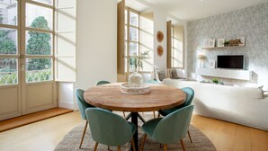 Un coin repas avec une table ronde en bois, des chaises de couleur turquoise et un vase servant de centre de table.