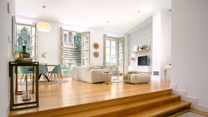 Un grand espace de vie comprenant un canapé, une table basse et une table à manger avec des chaises. Un escalier mène à un autre niveau.