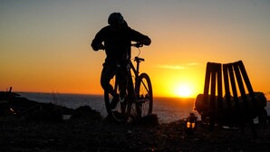 Eine Silhouette einer Person auf einem Fahrrad vor einem Sonnenuntergang.