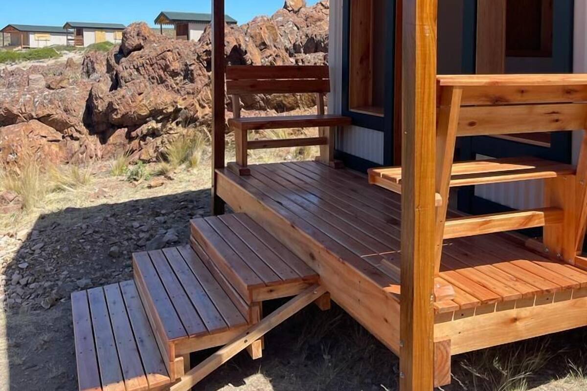 Una cabaña de madera con un porche, integrada en un terreno rocoso.
