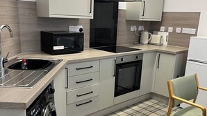 A compact kitchen with a dishwasher, microwave, oven, and a coffee maker. - Buckie Haven 3 Bed Contractors Business Travellers (Buckie)