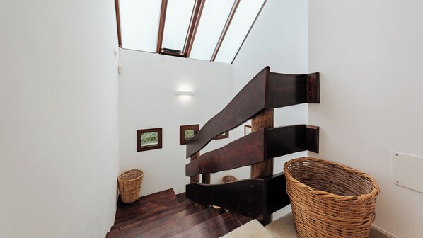 A modern staircase with dark wooden steps and handrails, leading to a lofted area with skylights.