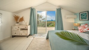 A bedroom with a bed, a nightstand, a dresser, and a view of the outdoors. - Manguier (Le Diamant)